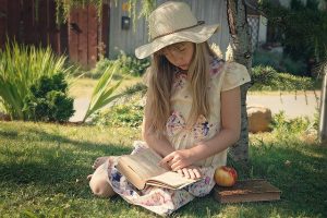 Una bambina sta leggendo un libro seduta in un prato