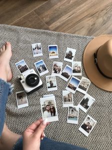 Lots of Polaroid photos spread out on the floor with a girl's foot close by.