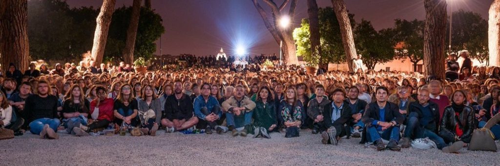 People sitting on the floor watching a movie at a screening organized by Cinema America in Rome.